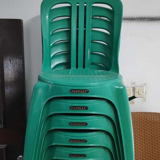 a green plastic chair in a room with a white wall.
