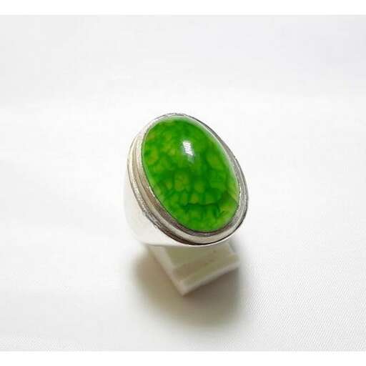 a ring that is very large and has a green stone in it.