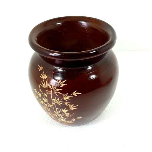 a brown and black vase with a gold design on it.