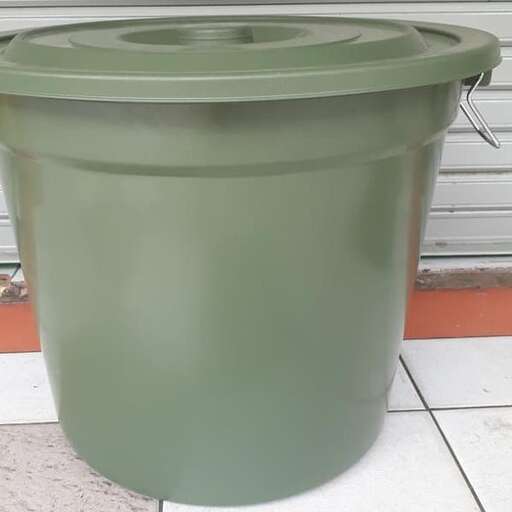 a large green plastic tub sits in front of a garage door.
