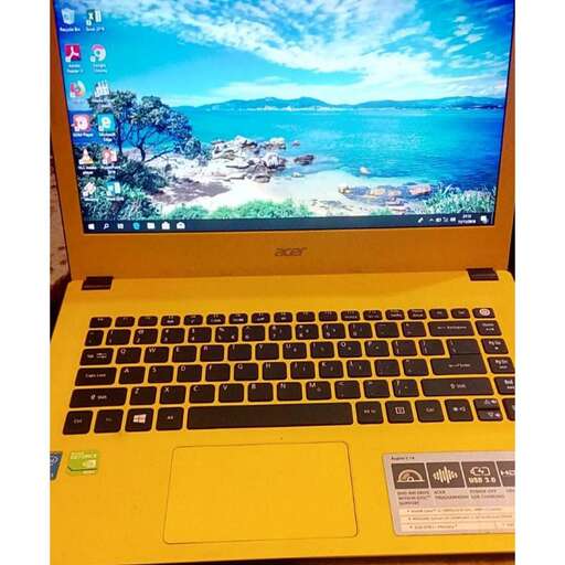 a yellow laptop computer sitting on top of a table.