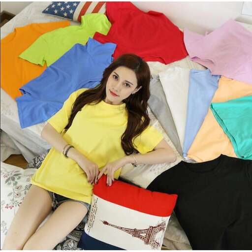 a woman in a yellow dress sitting on a bed with a pile of clothes.