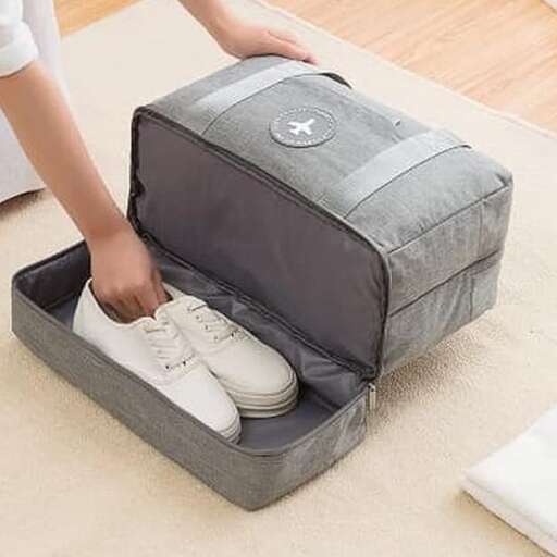 a person putting a shoe in a suitcase.