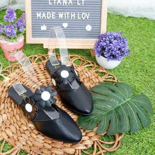 a pair of black shoes with a white flower in the middle.