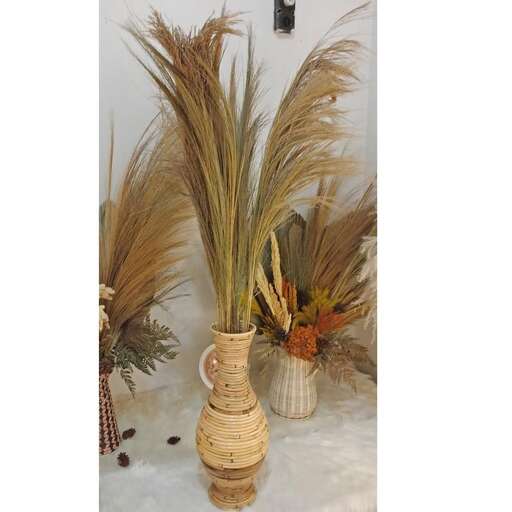 a vase with dried grass and dried plants.