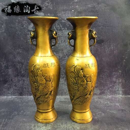 two golden vases are sitting on a table.