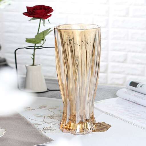a tall glass vase with a rose in it.