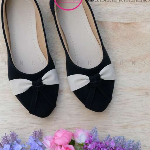 a pair of black shoes with a bow on the side.