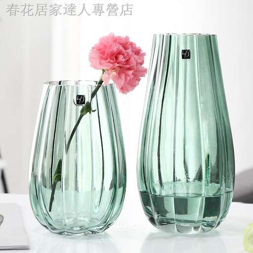 a vase with a pink flower in it on a table.