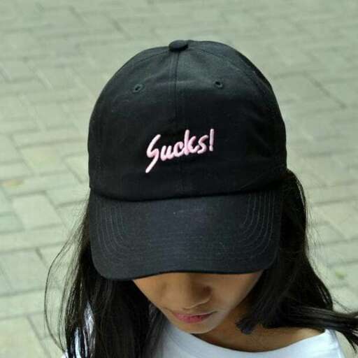 a little girl wearing a black hat with a message on it.