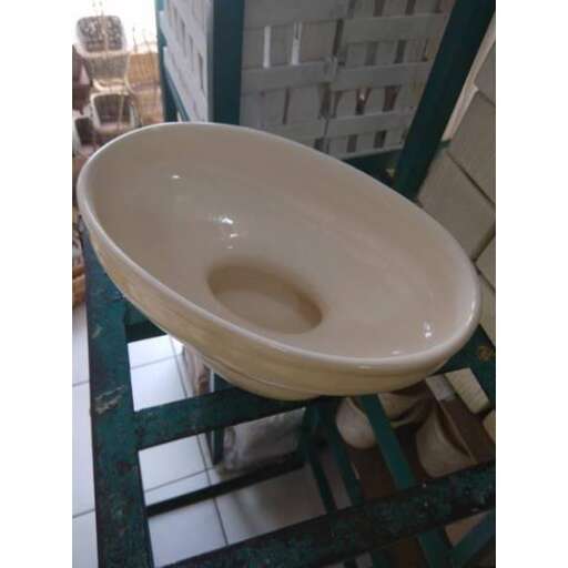a white toilet bowl sitting on top of a green metal stand.