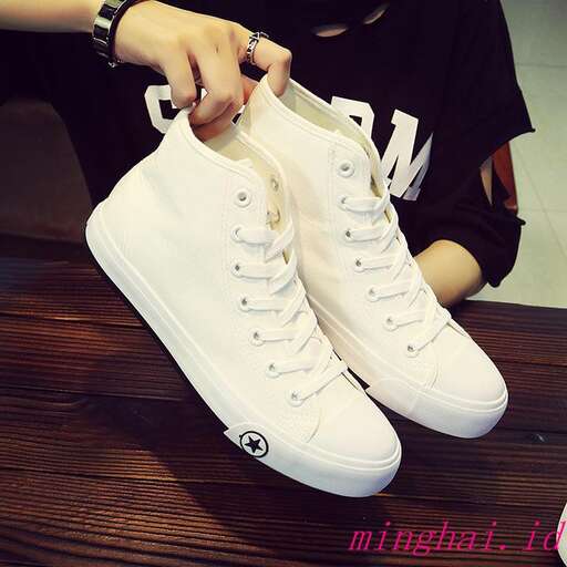 a person putting on a pair of white sneakers.