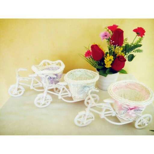a bicycle made out of three baskets and a basket of flowers.