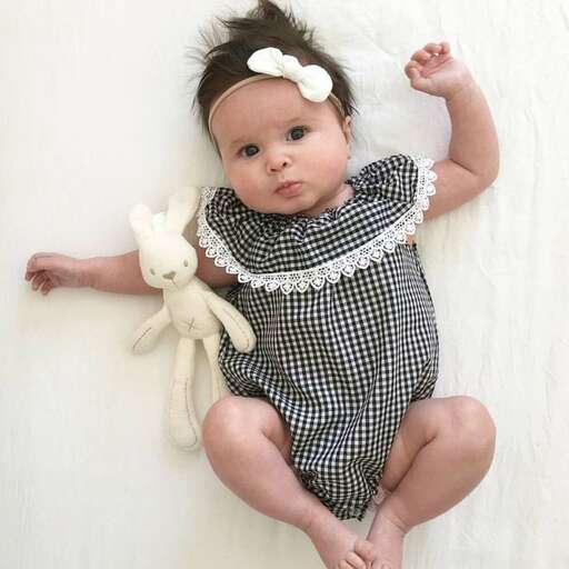 a baby is sitting on a white wall.