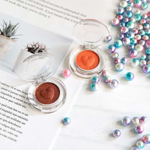 a photo of a table with a bottle of perfume and a flower.