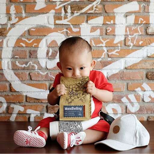 a baby sitting on a table with a piece of food in his mouth.