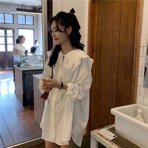 a woman in a white shirt and green shorts standing in a kitchen.