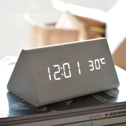 a digital clock is placed on a book.