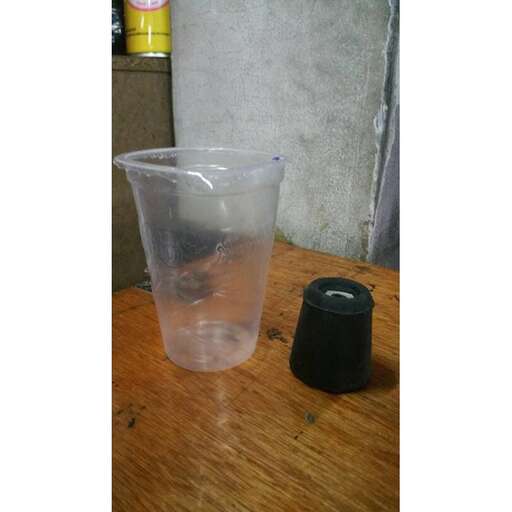 a plastic cup with a black lid sits on a table.