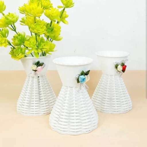 a white vase with flowers in it sitting on a table.
