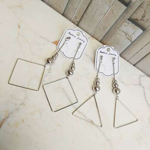 a pair of earrings with tags hanging on a white marble floor.