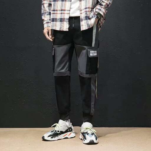 a man standing in front of a wall with his leg in a checkered shirt and leggings.