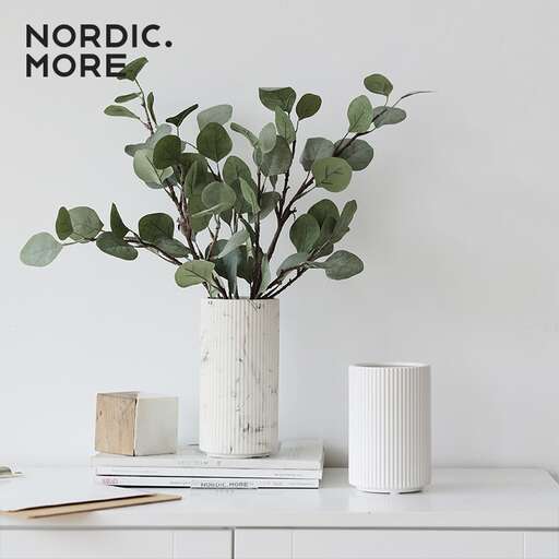 a white vase with a plant in it.