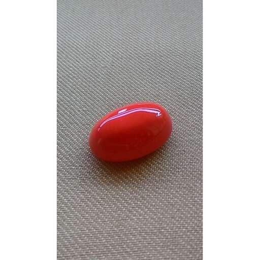 a red glass marble on a table in the park.