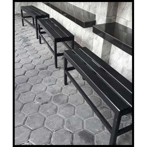 a black bench sitting next to a wall.