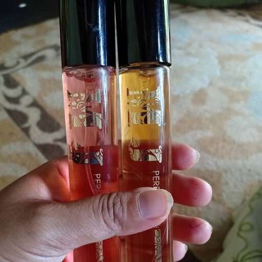 a person holding a bottle of perfume in their hand.