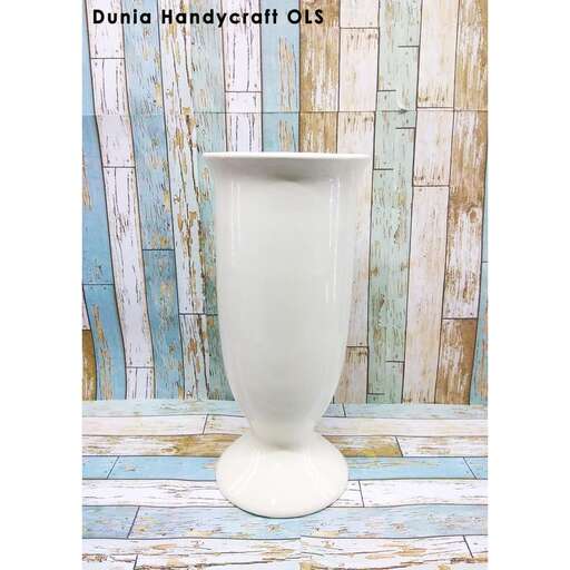 a white vase sitting on top of a wooden floor.