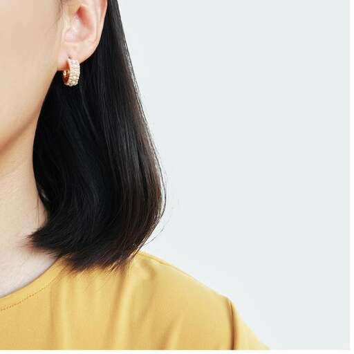 a woman wearing earrings in yellow shirt