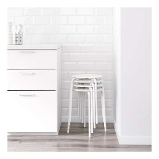 a white stool sitting in a kitchen next to a white wall.