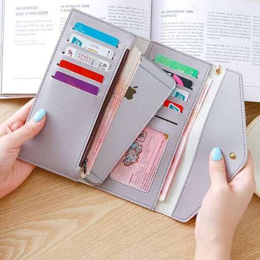 a woman's hand holding a wallet with a notepad and a pen.