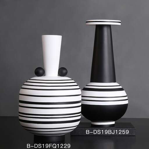 a black and white vase and a white vase on a table.