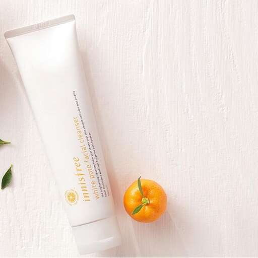 a white and green bottle of lotion and a tomato.