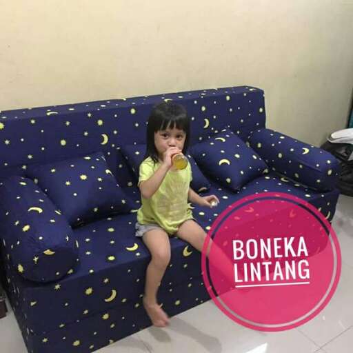 a little girl sitting on a couch eating a snack.