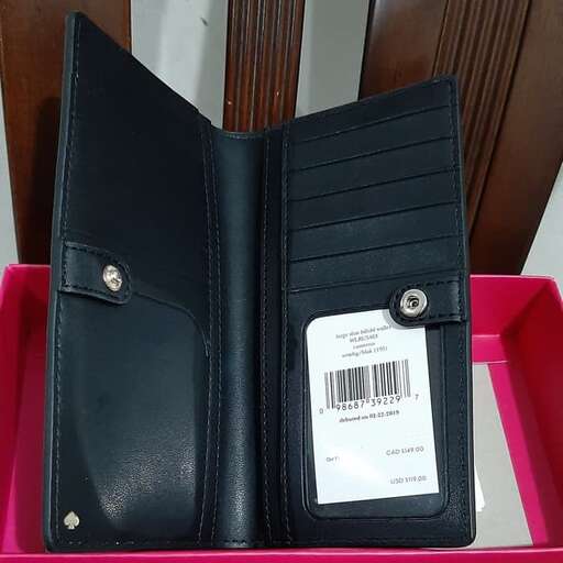 a black leather wallet sitting on top of a pink plastic container.