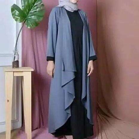 a woman in a black dress standing next to a table.