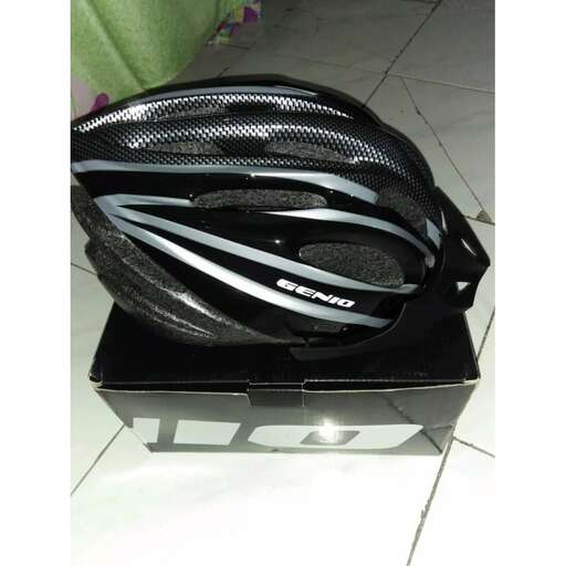 a black bike helmet is sitting on a white tile floor.
