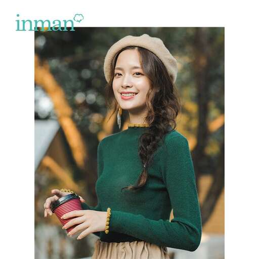 a woman in a green sweater holding a coffee cup.