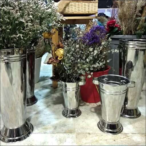 a table with three silver vases and flowers.
