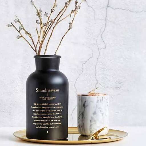 a vase with flowers and a candle on a plate.