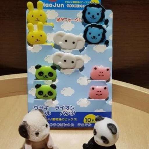 two stuffed pandas sitting on a table next to a box of pandas.