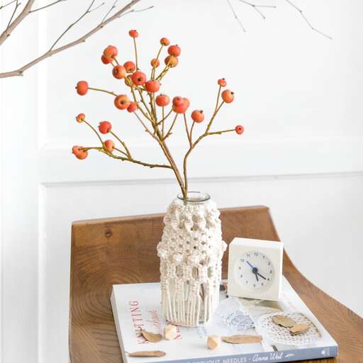 a vase with orange berries on a table.