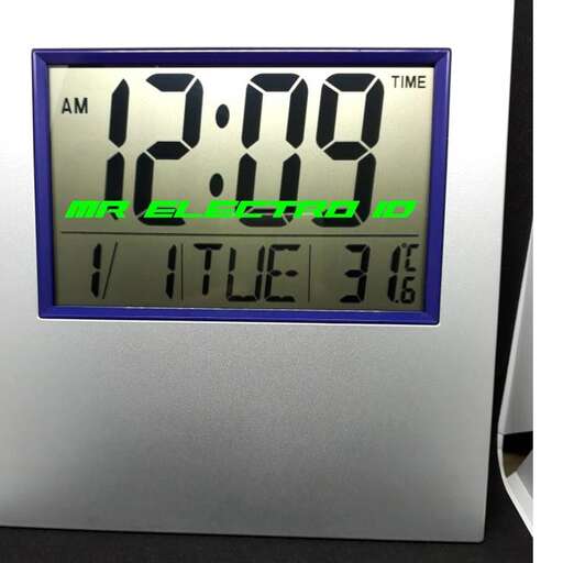 a digital clock with the time displayed on a table.