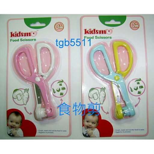 a baby in a red and blue outfit holding pink scissors.