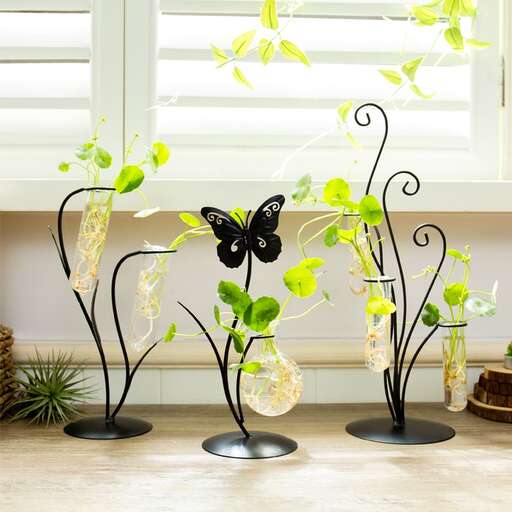 a set of three black metal flower vases with a butterfly in the middle.