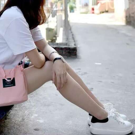 a woman sitting on a bench with her legs crossed.