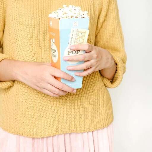 a woman holding a popcorn in her hands.